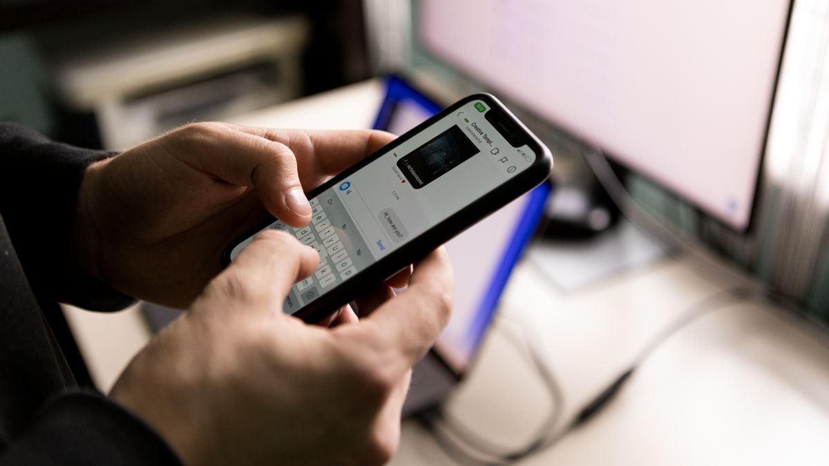 Person chatting on a smartphone beside a computer screen, representing a WhatsApp sign up