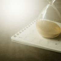 An hourglass resting on a calendar