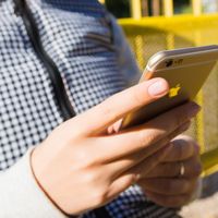 Close-up of a hand holding a smartphone outdoors, checking a signal-dependent app