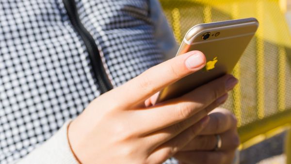 Close-up of a hand holding a smartphone outdoors, checking a signal-dependent app