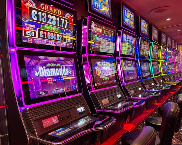 Colorful slot machines lined up in a casino with neon lights and jackpot displays
