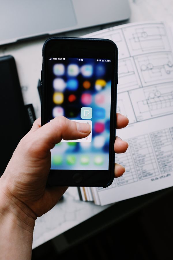 A hand holding a smartphone with an app icon visible on screen