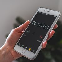 A hand holding a smartphone with a stopwatch app running