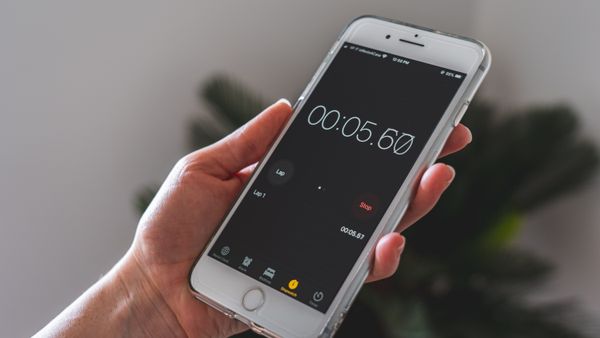 Close-up of a hand holding a smartphone with a stopwatch app running