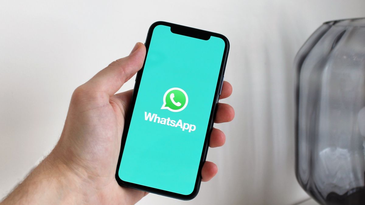 Close-up of a hand holding a smartphone displaying the WhatsApp app screen