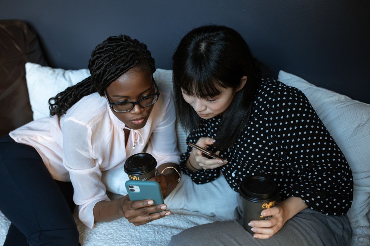 Two friends sitting together looking at a smartphone