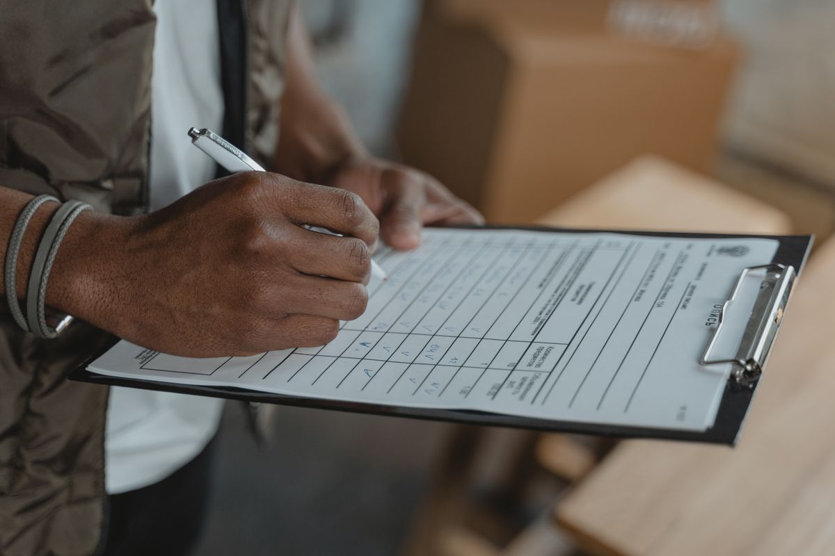 A person writing on a form attached to a clipboard