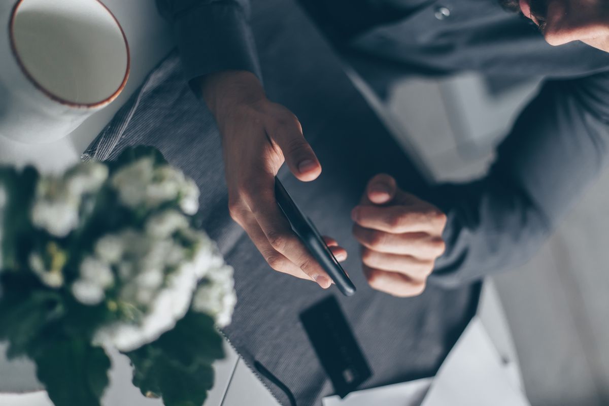 A person holding a smartphone in both hands, ready to take a screenshot of a bank transfer confirmation