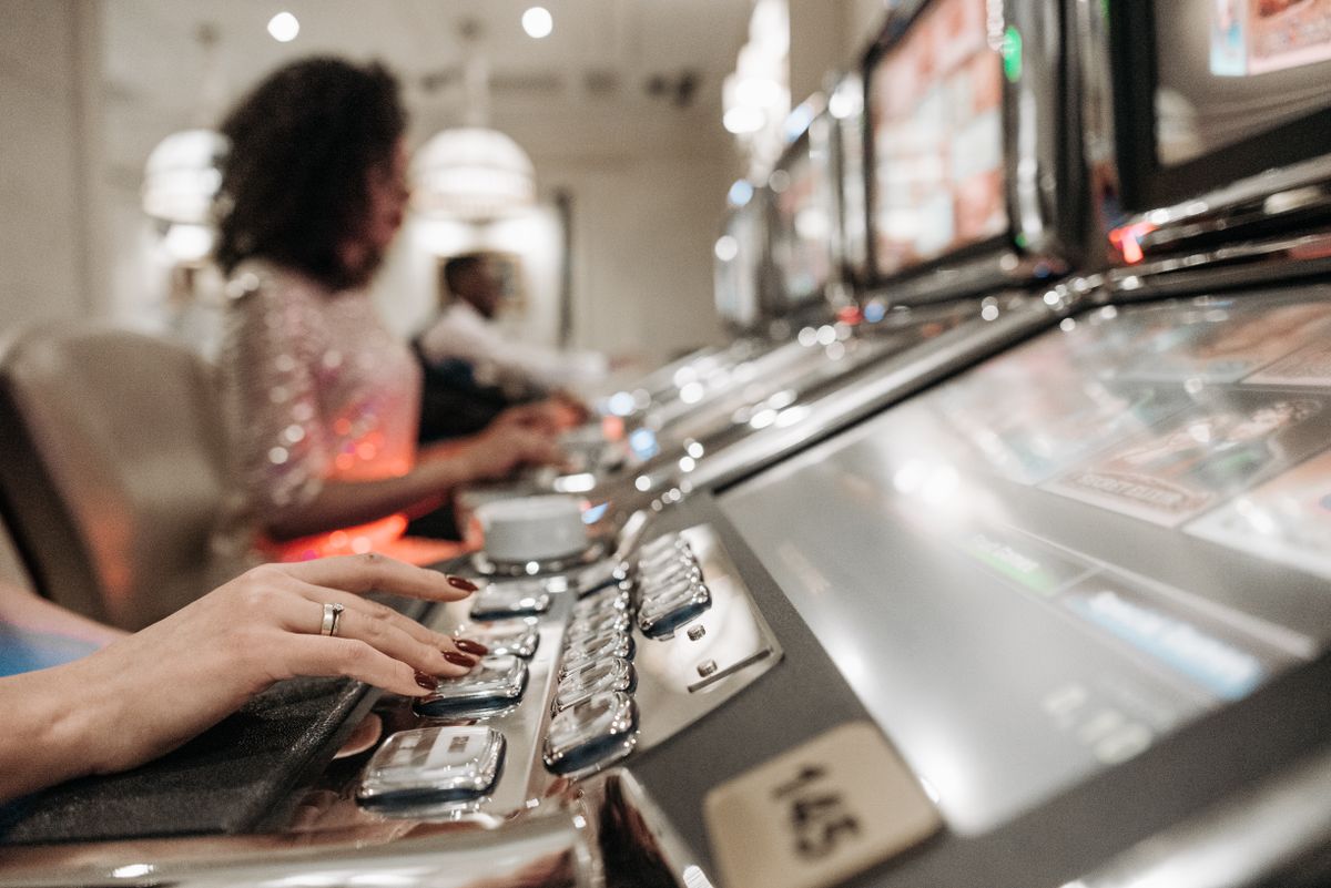 Close-up view of hands playing slot machines in a casino setting