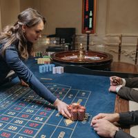A live dealer running a roulette game at a casino table