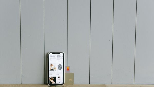 A smartphone beside a credit card on a wooden surface