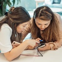 Two friends looking closely at a smartphone screen together
