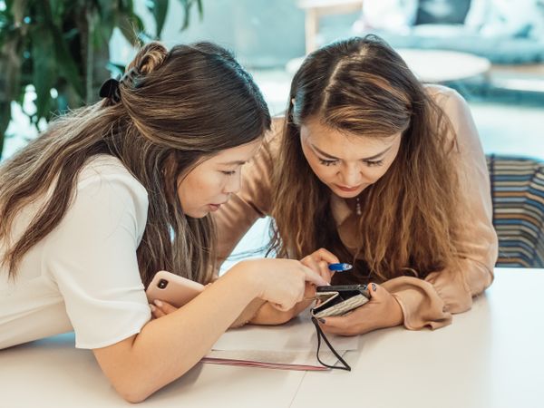 Two friends looking closely at a smartphone screen together