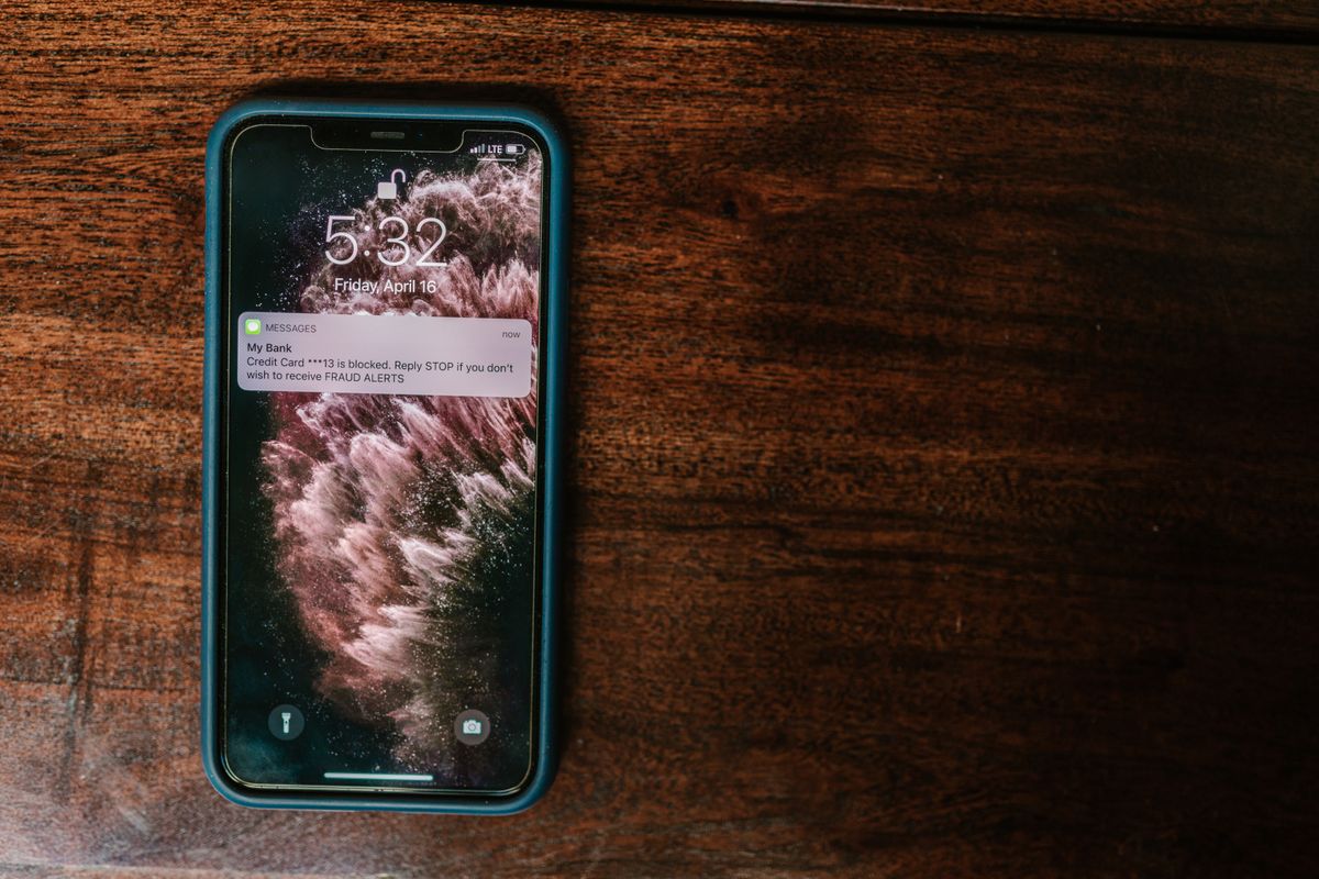 A smartphone on a wooden table displaying a bank alert message, like the SMS confirmation used as a deposit slip