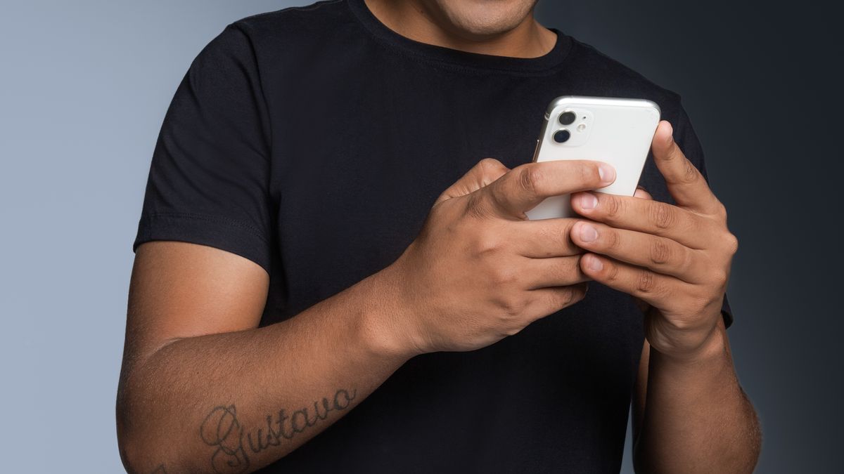 Man smiling while checking his phone, registering for a casino account