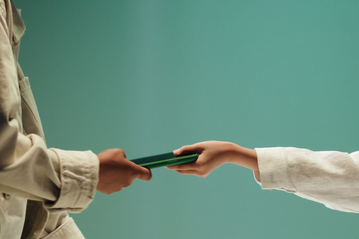 Two people exchanging a smartphone